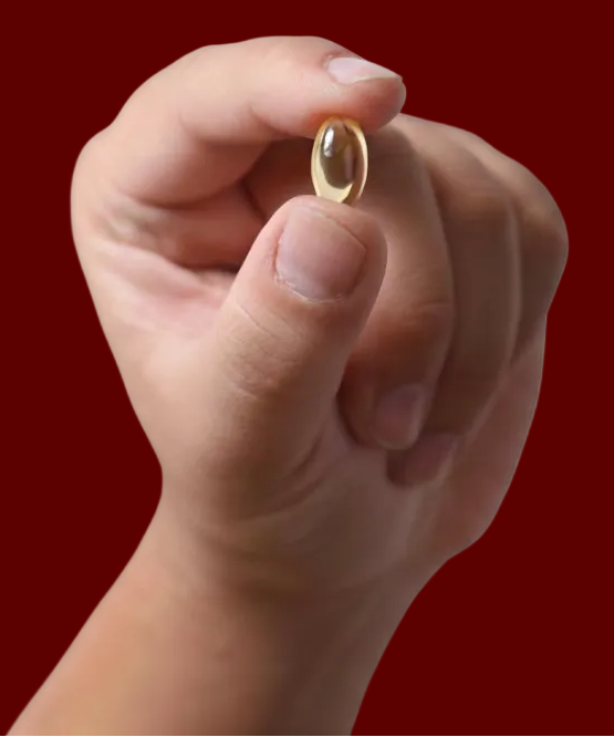 Hand holding a vitamin pill against a red background
