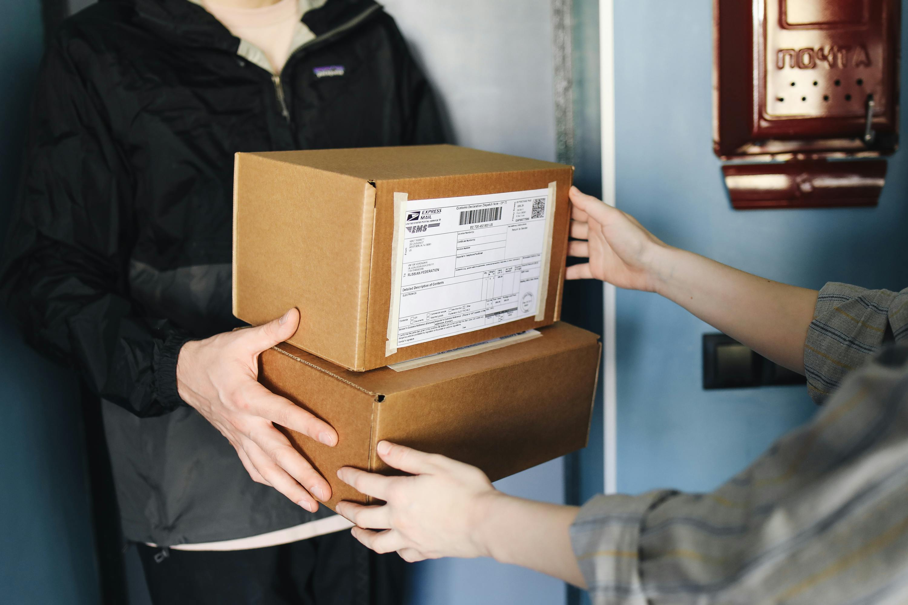 Person receiving a package from another person against a blue wall.