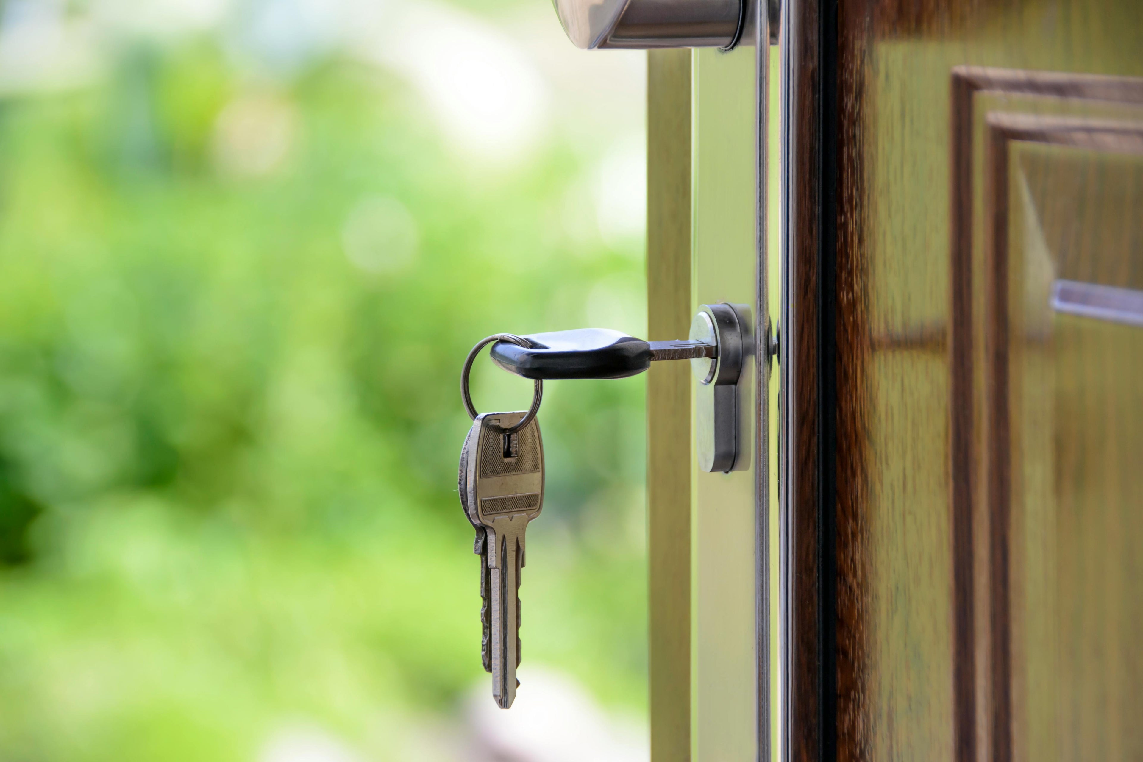 Keys hanging on a door handle with a blurred green outdoor background
